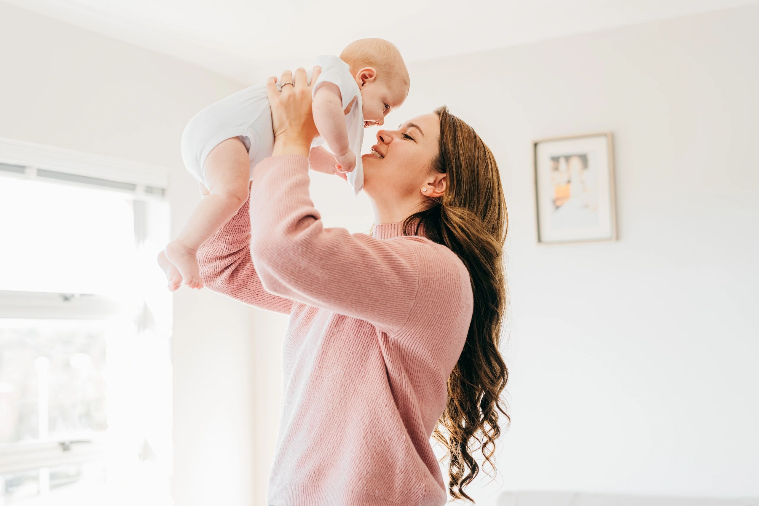 Mother holding baby in a bright living room