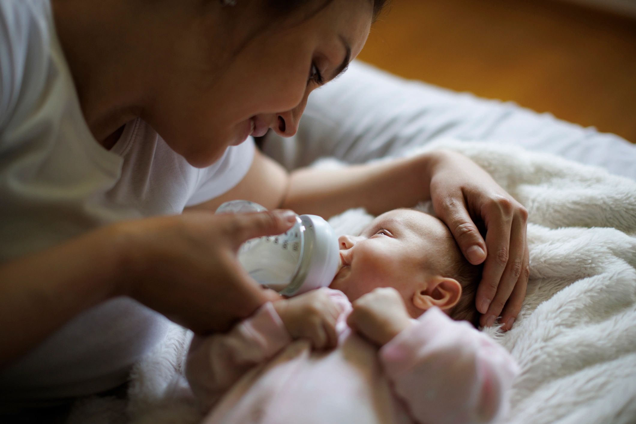 Mother feeding her baby with a bottle at home